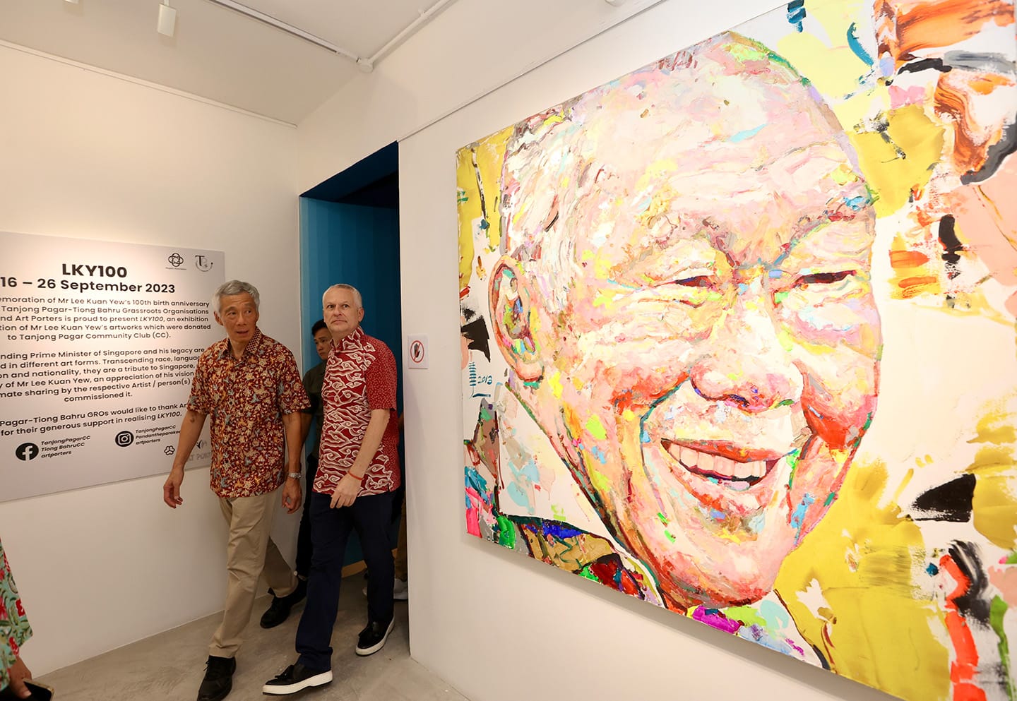 Men at LKY100 exhibit with large colorful portrait of Lee Kuan Yew.